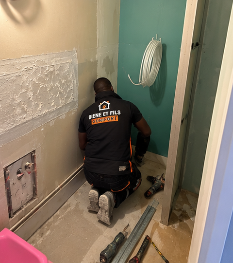 Plombier Diene et Fils Comfort installant un bâti-support de WC suspendu et une plaque hydrofuge dans une salle de bain