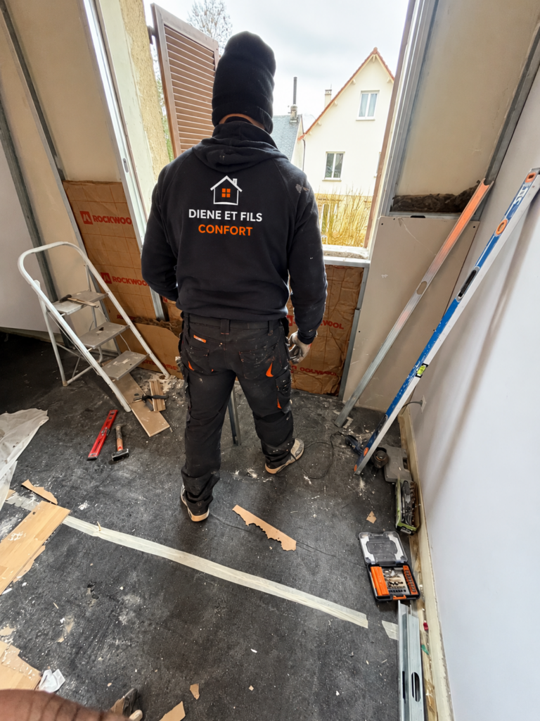 Ouvrier Diene et Fils Comfort préparant le doublage isolé autour d'une porte-fenêtre lors d'une rénovation